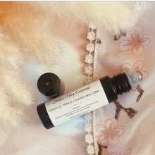 Load image into Gallery viewer, A small roll-on perfume bottle of Yellow Harp Essentials Orange Petals + Mars-Mallow scent with its cap off, resting on a soft cream faux fur surface with a floral satin fabric underneath.