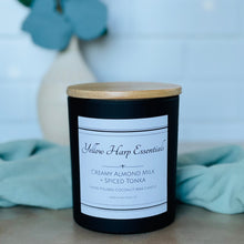 Load image into Gallery viewer, highly scented creamy almond milk and spiced tonka coconut wax candle with crackling wood wick in reusable black glass jar and wood lid
