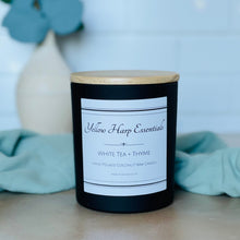Load image into Gallery viewer, Highly scented white tea and thyme coconut wax candle with crackling wood wick in reusable glass black jar with wooden lid