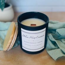 Load image into Gallery viewer, Candle in a black container with a label on a wooden surface