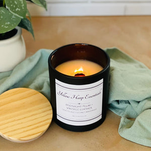 highly scented coconut wax candle with crackling wood wick midnight plum and vintage leather scent black glass reusable jar wooden lid