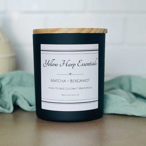 yellow harp essentials highly scented hand poured coconut wax candle with crackling wood wick in glass black jar with wood lid. Matcha and bergamot scent