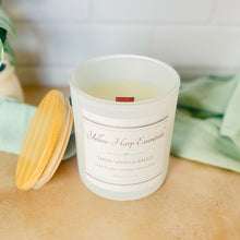 Load image into Gallery viewer, White glass jar with wood lid and Yellow Harp Essentials label with Sheer Vanilla Breeze scent and greenery background
