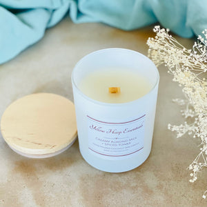 highly scented creamy almond milk spiced tonka coconut wax candle with crackling wood wick in reusable white glass jar and wood lid