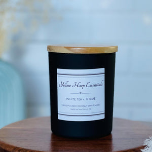 highly scented white tea thyme coconut wax candle with crackling wood wick in reusable black glass jar and wood lid