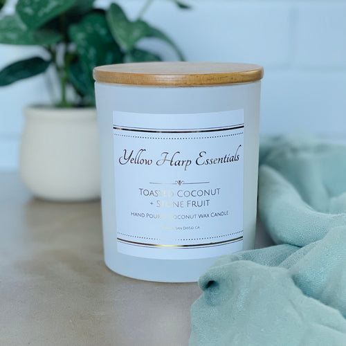 highly scented toasted coconut and stone fruit coconut wax candle with crackling wood wick in reusable white glass jar and wood lid
