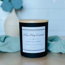 Load image into Gallery viewer, Highly scented white tea and thyme coconut wax candle with crackling wood wick in reusable glass black jar with wooden lid
