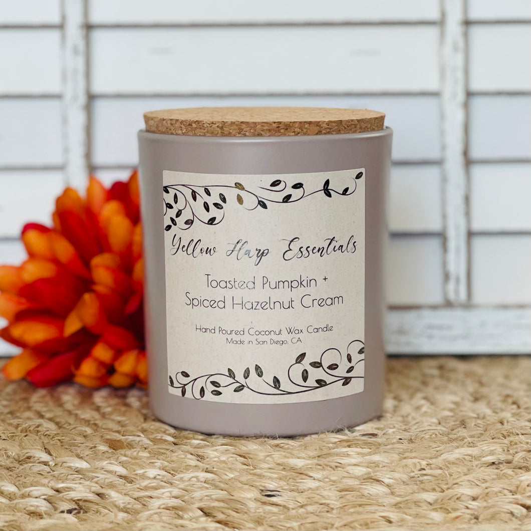 Hand poured coconut wax candle with natural crackling wood wick highly scented long lasting toasted pumpkin and spiced hazelnut cream fragrance taupe colored glass jar cork lid reusable sustainable 